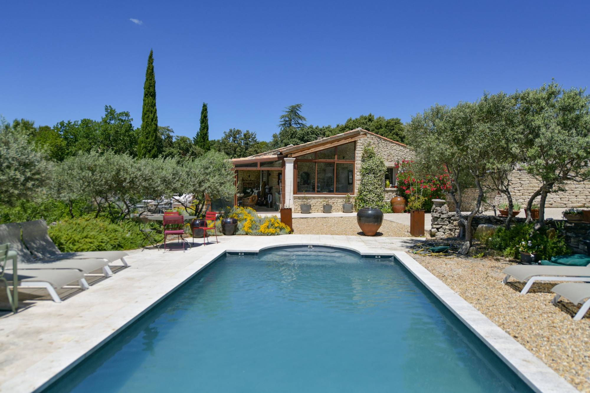 Proche du village de Gordes, à vendre agréable maison de en pierre apparente de 4 chambres sur terrain arboré avec piscine et pool house.