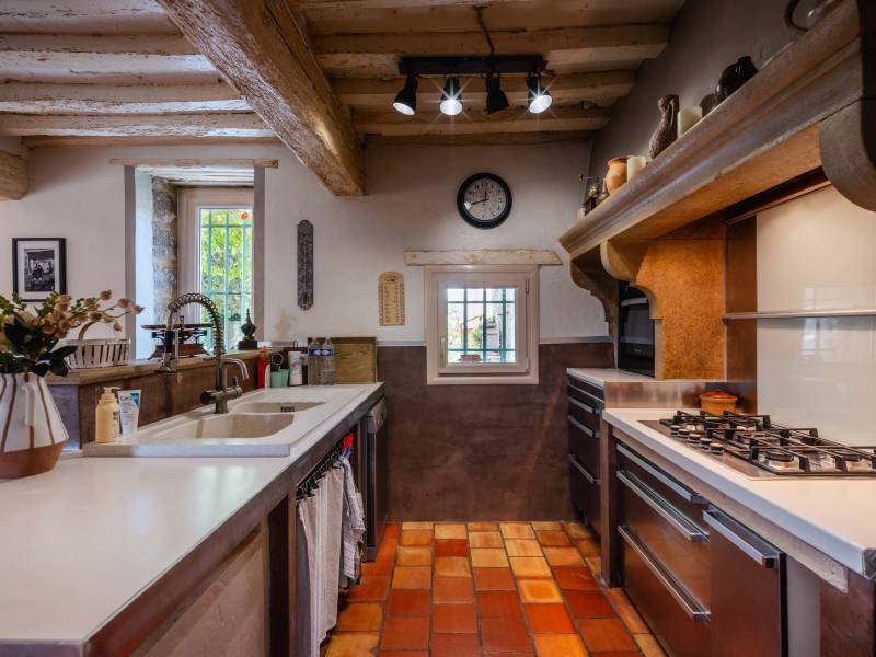 Cuisine moderne et fonctionnelle : Agencements contemporains et équipements de qualité s'intégrant parfaitement dans le cadre historique de la ferme.