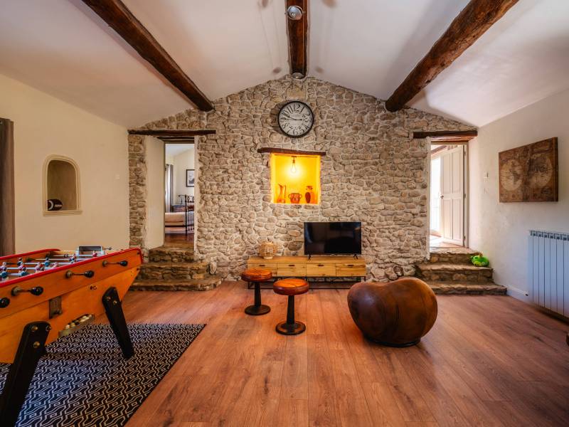 Espace loisirs familial : Salle de jeux spacieuse sous charpente apparente, témoignant de la rénovation de qualité de cette demeure de 360 m².