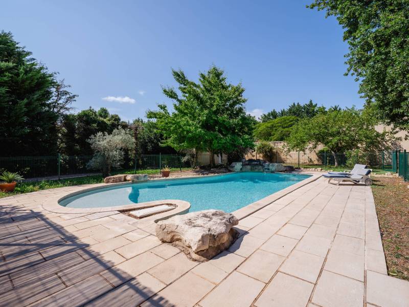 Espace baignade haut de gamme : Piscine Diffazur de forme libre avec cascade, nichée dans un jardin paysager entièrement clos.