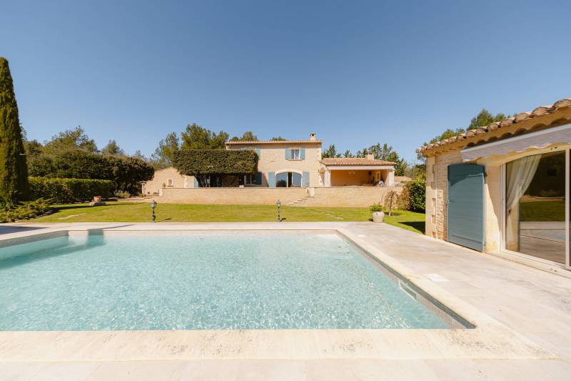 Entre Gordes et Cabrières d'Avignon, face au Luberon et ses villages perchés, propriété en pierres avec piscine chauffée, pool house et dépendances à vendre en Provence.