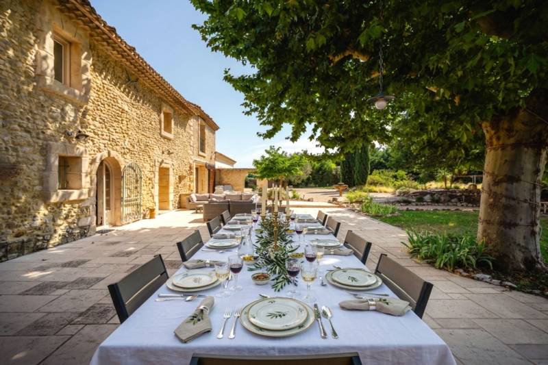 L'art de vivre en Provence : Espace repas élégant sur la terrasse spacieuse, idéalement ombragé par un chêne centenaire pour vos réceptions estivales.